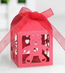 Detailed close-up of hollow bear-shaped candy gift box with red organza ribbon bow