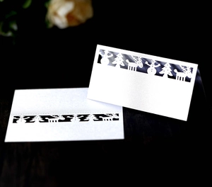 Laser-cut white paper Christmas place cards featuring deer, snowman, and tree patterns