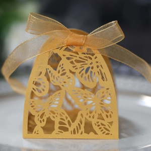 Detailed laser-cut golden butterfly wedding favor box with a delicate silk ribbon bow