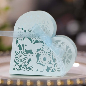 Close-up of light blue laser-cut heart favor box with butterfly pattern and ribbon