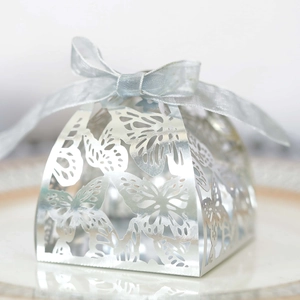 Close-up of laser-cut butterfly wedding favor box in silver pearl paper with ribbon