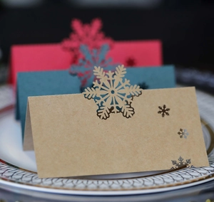 Marque-places de Noël découpés au laser en rouge, vert et papier kraft sur une assiette décorée