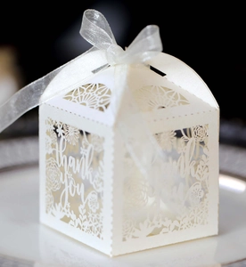 Detail of white laser-cut hollow thank you candy gift box with elegant silver ribbon bow