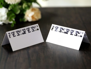 White laser-cut Christmas place cards featuring snowflake and reindeer designs on wood