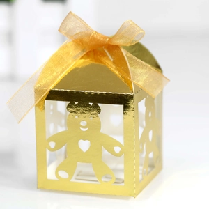 Close-up of golden metallic candy box featuring hollow bear cutouts and a yellow ribbon bow
