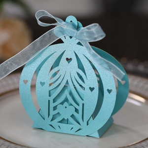 Laser-cut light blue pumpkin carriage wedding favor box with ribbon detail on a plate