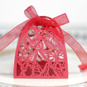 Macro view of red laser-cut wedding favor box with butterfly patterns and ribbon bow