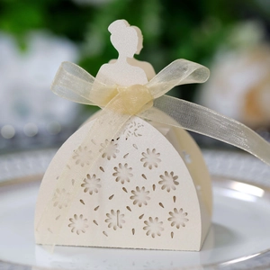 Detail of laser-cut wedding favor box with floral dress silhouette and champagne ribbon