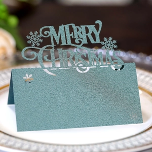 Close-up of laser-cut Merry Christmas place cards with glitter finish on a dinner plate