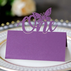 Macro detail of laser-cut purple butterfly place card with One lettering on a porcelain plate