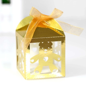Macro detail of golden hollow-out bear gift box with a translucent silk ribbon bow