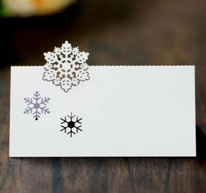Close-up of white snowflake place card with laser-cut detail on dark wood surface