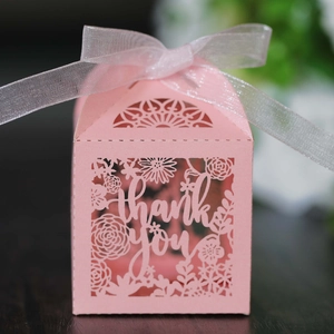 Close-up of pink laser-cut favor box with thank you text and white organza ribbon