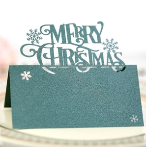 Macro detail of laser-cut snowflake and Merry Christmas text on green pearlescent card