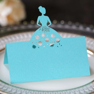 Close-up of sky blue laser-cut place card with dress silhouette on decorative plate