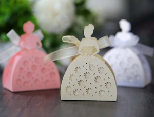 Detail of laser-cut wedding favor boxes in bridal gown shape with satin ribbon bows