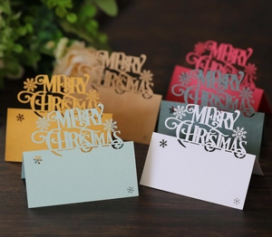 Detailed view of laser-cut Christmas place cards with snowflake and festive lettering