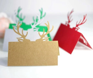 Primo piano di segnaposti natalizi con corna di renna in colori kraft, rosso e verde festivo