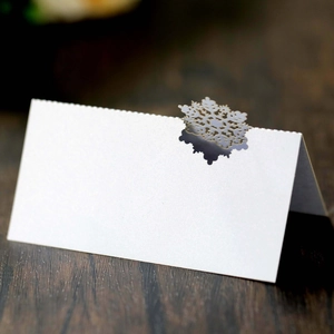 Close-up of laser-cut snowflake place card on a rustic wood background for winter wedding