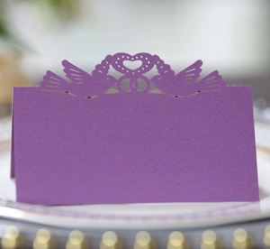 Close-up of purple laser-cut place card with love birds on a white plate with gold rim