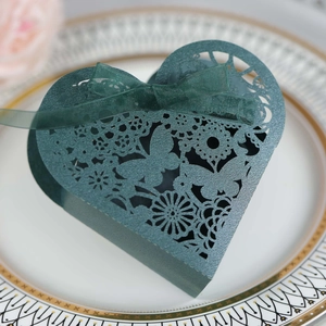 Macro detail of laser-cut heart candy box with butterfly floral patterns and ribbon