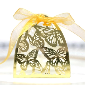 Macro detail of gold laser-cut butterfly wedding favor box with a silk ribbon bow