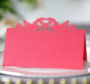 Macro shot of laser-cut red place cards with heart and bird motifs for weddings
