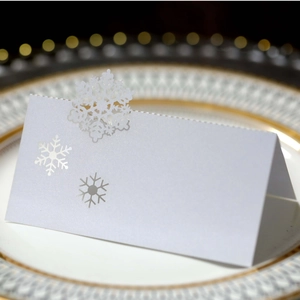 Macro detail of laser-cut snowflake place card on an elegant white dinner plate