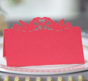 Macro detail of red laser-cut place card with bird and heart pattern on a dinner plate