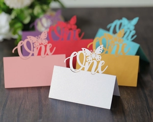 Laser-cut butterfly place cards with 'One' lettering in multiple pearlescent colors