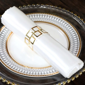 Macro shot of gold geometric hollow napkin ring on a white linen napkin for wedding decor