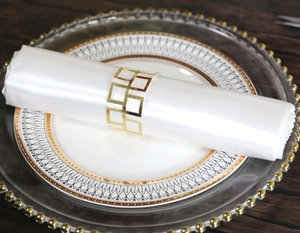 Golden geometric napkin ring with square hollow design on white silk napkin detail