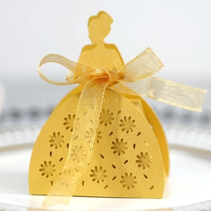 Detailed laser-cut yellow princess candy box with organza ribbon on a porcelain plate