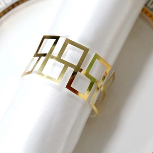 Detail view of gold geometric hollow napkin ring on a white napkin and porcelain tray