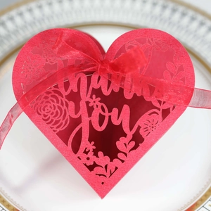 Macro view of red laser-cut heart favor box with thank you text and silk ribbon detail
