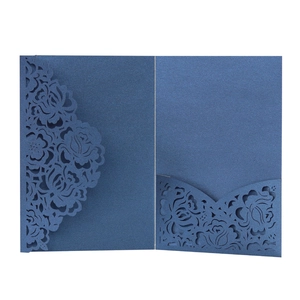 Macro view of laser-cut rose patterns on navy blue pearlescent wedding invitation card