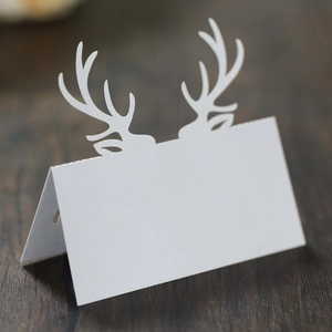 Macro di un segnaposto bianco pieghevole con corna di alce intagliate per tavola di Natale