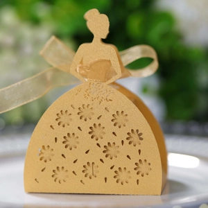 Macro view of laser-cut gold wedding favor box featuring elegant floral gown patterns
