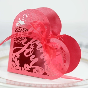 Macro detail of laser-cut heart favor box with Love pattern and red organza ribbon