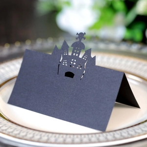 Macro view of laser-cut black castle Halloween place card on an elegant porcelain plate