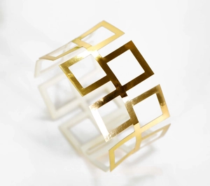 Macro shot of gold napkin ring featuring a hollow geometric square pattern and mirror finish