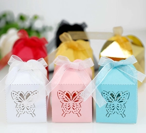 Close-up of laser-cut butterfly patterns on colorful candy boxes with organza ribbons