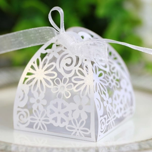 Close-up of white laser-cut hollow floral wedding candy box with elegant ribbon bow