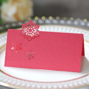 Detail showing red laser-cut snowflake place card on a white plate for Christmas parties