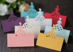 Macro detail of laser-cut wedding place cards featuring elegant female silhouettes and hollow flowers