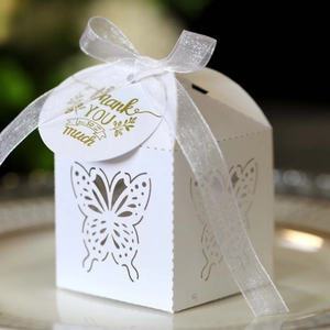 Close-up of laser-cut butterfly gift box with white organza ribbon and golden gift tag