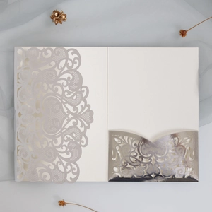 Macro detail of laser-cut hollow pattern and card slot on silver wedding invitation