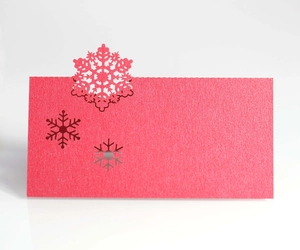 Close-up of red snowflake place card with intricate laser cutouts and textured paper