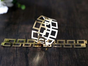 Detailed view of hollow square geometric gold napkin rings on a wooden surface