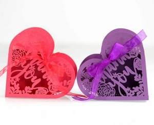 Detail of laser-cut heart favor boxes in red and purple with Thank You text and ribbons